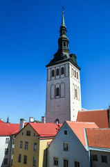The view of bell tower of the medieval Former Lutheran Church of St. Nicholas (Niguliste Kirik), bright roofs and colorful houses in the old historical center of Tallinn, Estonia