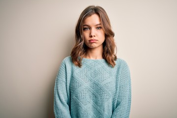 Young blonde girl wearing casual blue winter sweater over isolated background depressed and worry for distress, crying angry and afraid. Sad expression.