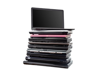 Stack of used laptops in different colors and models. T