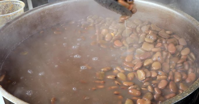 Cooking Vicia faba beans in a pot with steam hot water.