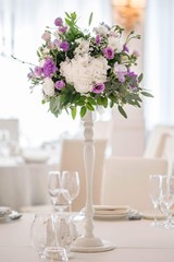 Wedding table decorated on mauve color. Centerpiece full of violet flowers in the middle