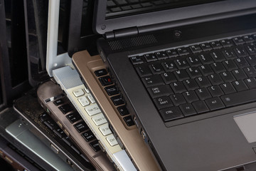 Stack of used laptops in different colors and models. T