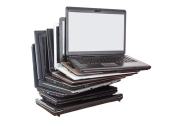 Stack of used laptops in different colors and models. T