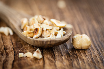 Freshly chopped Hazelnuts on an old wooden table (close up; selective focus)