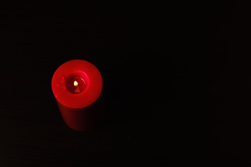 Red candle isolated on black background with a flame burning