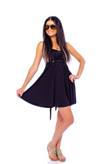 Naklejka premium Young beautiful brunette in a black dress in sunglasses on a white background