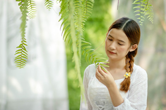 Defocused and blurred image for background. An Asian woman feels standing under a tree. Look at the leaves with sad eyes. Loneliness alone. coye space. bokeh green.