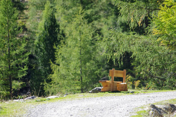 wooden bench to rest hikers and admire the high mountain with lake, meadows, woods and rocks