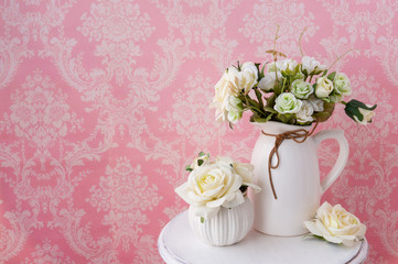 Fabric flowers on a vintage table on a pink background with a vintage pattern.