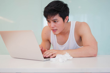 close up young man in pajamas using laptop to looking porn movie from website alone in bedroom for lifestyle and sexual behavior concept	