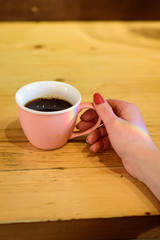 Pink coffee cup with hot beverage in womans hand with rainbow