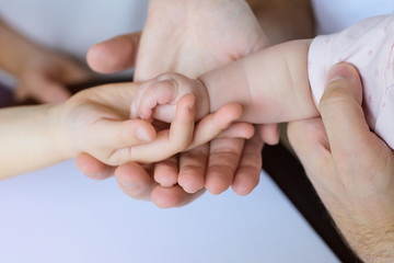 Four hands of the family, a baby, a daughter, a mother and a father.
