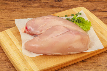 Raw chicken breast over board