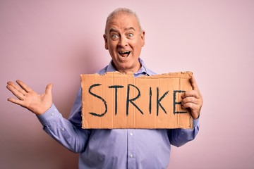 Middle age man asking for rights holding banner with strike message over pink background very happy and excited, winner expression celebrating victory screaming with big smile and raised hands