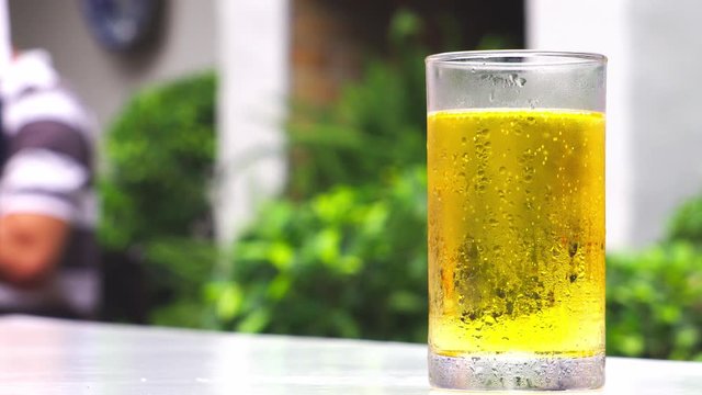 A yellow beer mug placed on a table with a blurred background