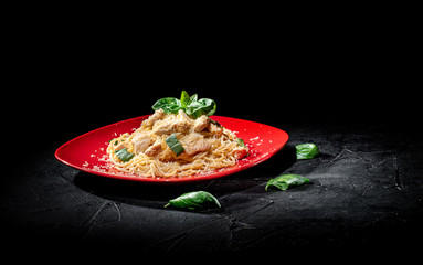Tasty appetizing classic italian spaghetti pasta with chicken, cheese on dark background