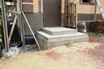 Fototapeta na wymiar Building poured concrete front porch steps to the entrance door of a brick house under construction.
