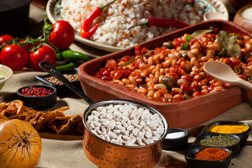 cooked and uncooked haricot beans, served with traditional cooked rice and table garnished with several legumes, vegetables and seasonings. Rich cuisine and dining table, delicious food.