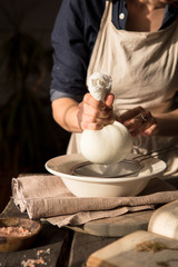 Preparation of cottage cheese - woman straining the milk through a cheesecloth