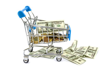 dollars and coins in a blue shopping trolley isolated on a white background.