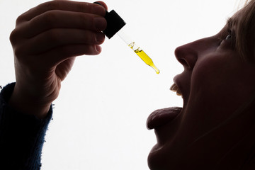 Silhouette of a woman taking drops of CDB oil