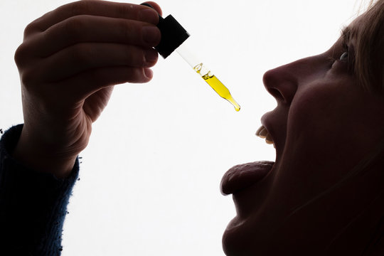 Silhouette of a woman taking drops of CDB oil