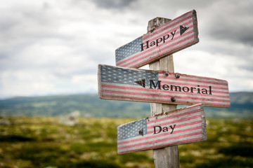 Happy memorial day text on wooden american flag signpost outdoors in nature.