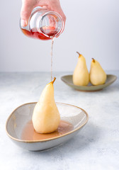 Poached pears with spices in syrup on the white plate. Delicious dessert for holiday. Scandinavian look. Poster concept.