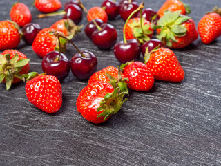 Fresh cherries and strawberries on a black background - 347900393