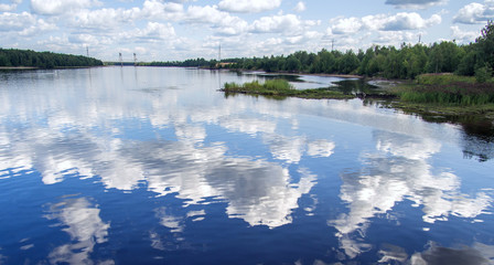 Landscape on the river on a sunny day. Clouds reflected in the river - 347900716