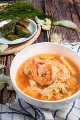 Mixed shrimp curry in a white bowl on a wooden background.
