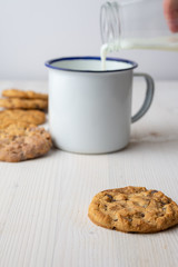 Close-up of biscuit with cup and bottle serving milk, with selective focus, white background, vertical