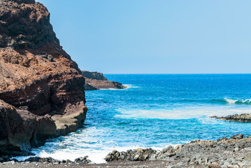 Fototapeta na wymiar Ocean rocky shore near the cape Teno, Tenerife. Voulcanic rocks with a bright and vibrant blue sea waves. Sunny day on Canary islands