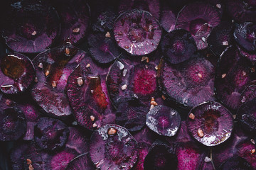 Slices of purple carrot with pink salt and olive oil for roasting. Macro photography, top view.
