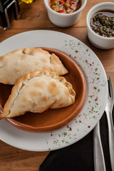 Traditional Argentine empanadas, on wooden table in gourmet restaurant.