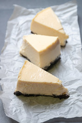 Creamy cheesecake with chocolate cookies slice on baking paper with black tray.
