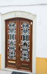 old wooden door with ornate metal grille across the glass
