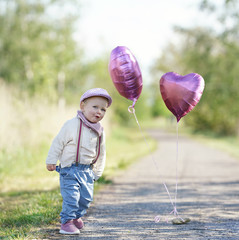 kleines fröhliches Mädchen im Park mit Luftballons