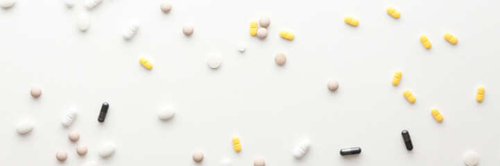 Colorful pills scattered on a white background. Panorama