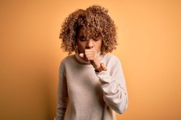 Fototapeta na wymiar Young beautiful african american woman wearing turtleneck sweater over yellow background feeling unwell and coughing as symptom for cold or bronchitis. Health care concept.