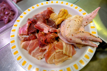 Close up raw slice pork chicken wings ,liver in plate prepare for barbecue.