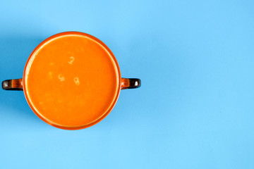 tomato soup in a brown plate with handles top view on a blue background .gluten-free vegan food ....