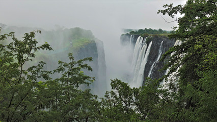 Miracle of nature Victoria Falls in Zambia. Powerful streams of water from the Zambezi River fall into the gorge from steep cliffs. Water fog is like smoke. An incredible sight.