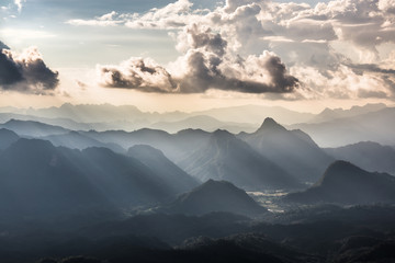 Golden light rays from clouds shining down to mountains. Sun rays over valley. Sun rays over hill. Beam of light from clouds on the mountains. Heaven in nature. Mon Pui Mok, Mae Moei, Tak, Thailand. © cattyphoto