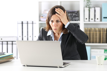 Surprised executive lady making mistake on laptop at office
