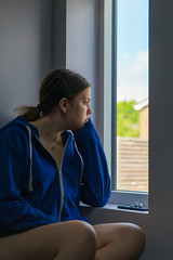 Shot of a bored teenage girl looking out of window