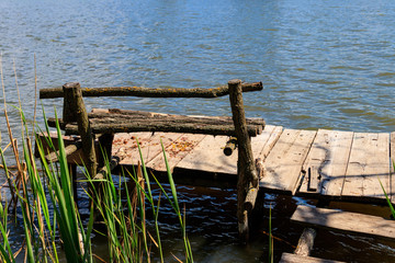 Fototapeta premium Small wooden pier with bench for fishing on a lake