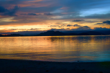 Fototapeta na wymiar Bright colorful sunset over the sea, mountains on the horizon. Indonesia, view from Gili Asahan island to Lombok.
