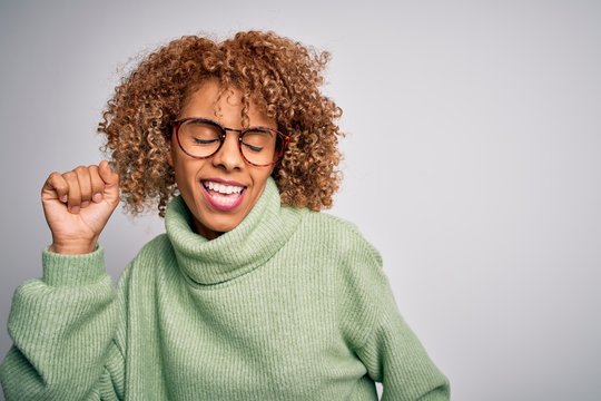 Young beautiful african american woman wearing turtleneck sweater and glasses Dancing happy and cheerful, smiling moving casual and confident listening to music