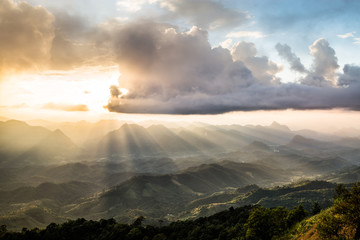 Golden light rays from clouds shining down to mountains. Sun rays over valley. Sun rays over hill. Beam of light from clouds on the mountains. Heaven in nature. Mon Pui Mok, Mae Moei, Tak, Thailand.
